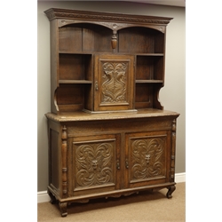  Late 19th century heavily carved oak dresser, raised back with lunette cornice above shelves and panelled cupboard carved with sea beasts, bow front bottom section with panelled doors, acanthus leaves and green man icon, on scrolled feet, labelled 'Bowman Brother, Camden', W142cm, H205cm, D54cm  