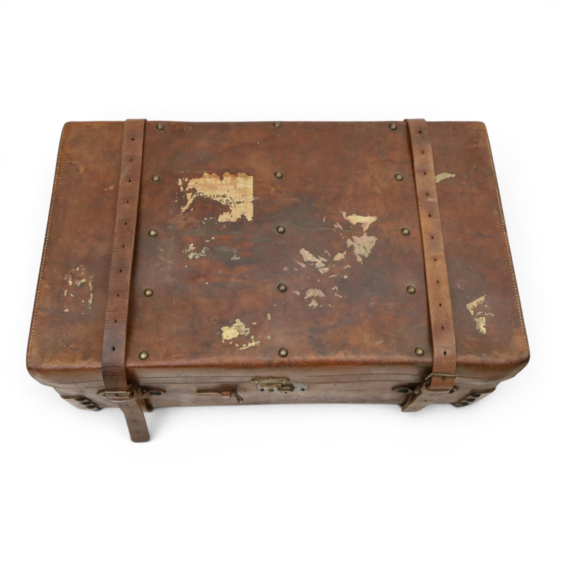 19th century leather trunk, featuring brass lock, with leather anchoring straps around the body, with leather handles