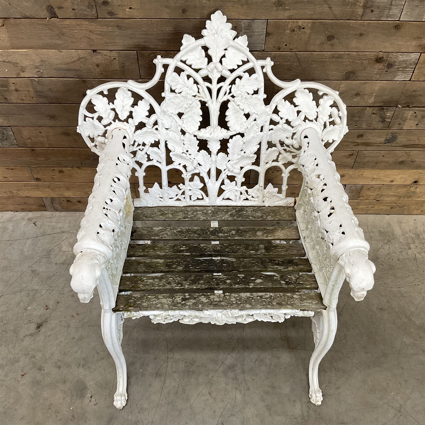 20th century Coalbrookdale design cast iron oak leaf and acorn armchair, white painted cast iron frame with slatted wooden seat, the pierced and shaped back decorated with scrolling oak branches and leafage, flanked by dog mask arm terminals over cabriole supports with paw feet