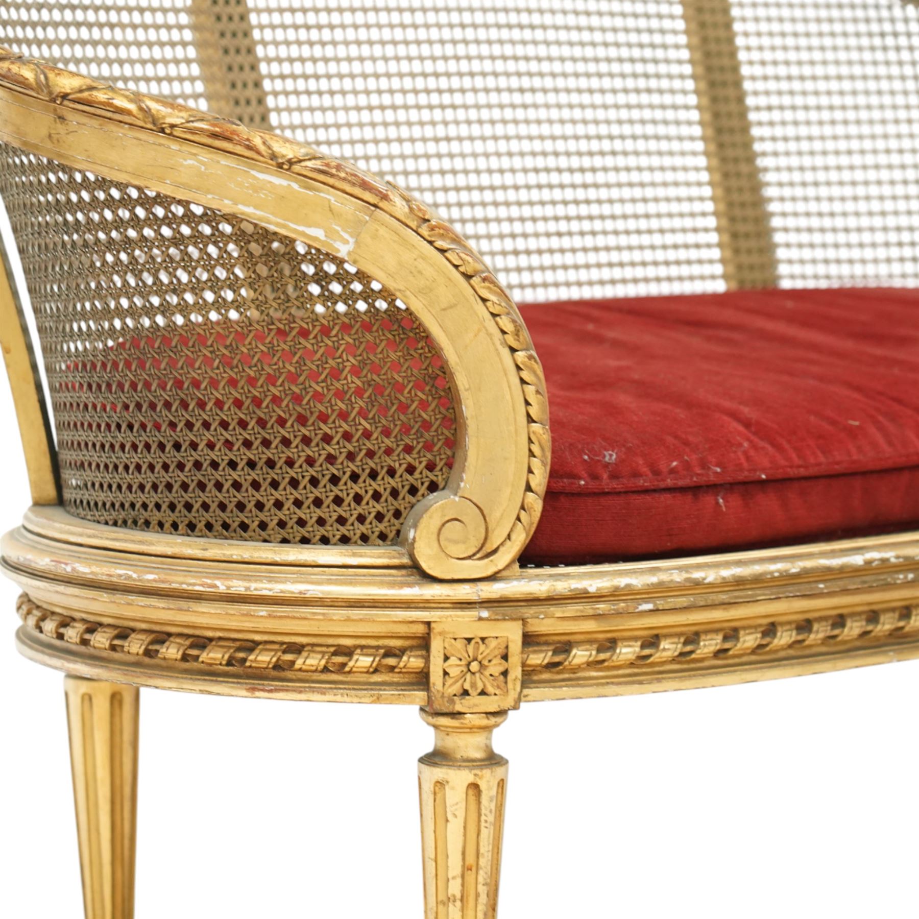 19th century giltwood and gesso settee, with shaped crest rail centred by carved floral detail, the cane back with vertical divisions, upholstered seat with loose cushion, raised on fluted tapering legs