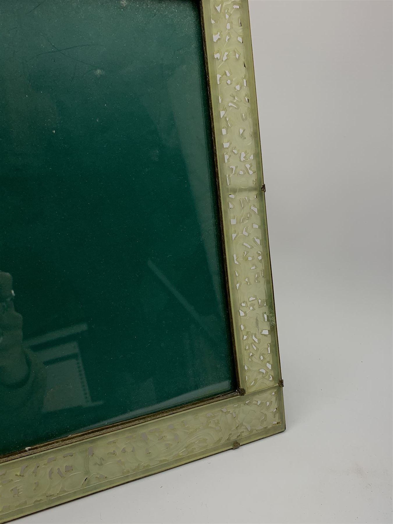 Early 20th century Chinese jade mounted photograph frame, of rectangular form the pierced jade frame carved with flowers and birds, the top panel carved with Foo dogs flaking an applied carved lavender coloured boss, with easel support verso, H33cm
