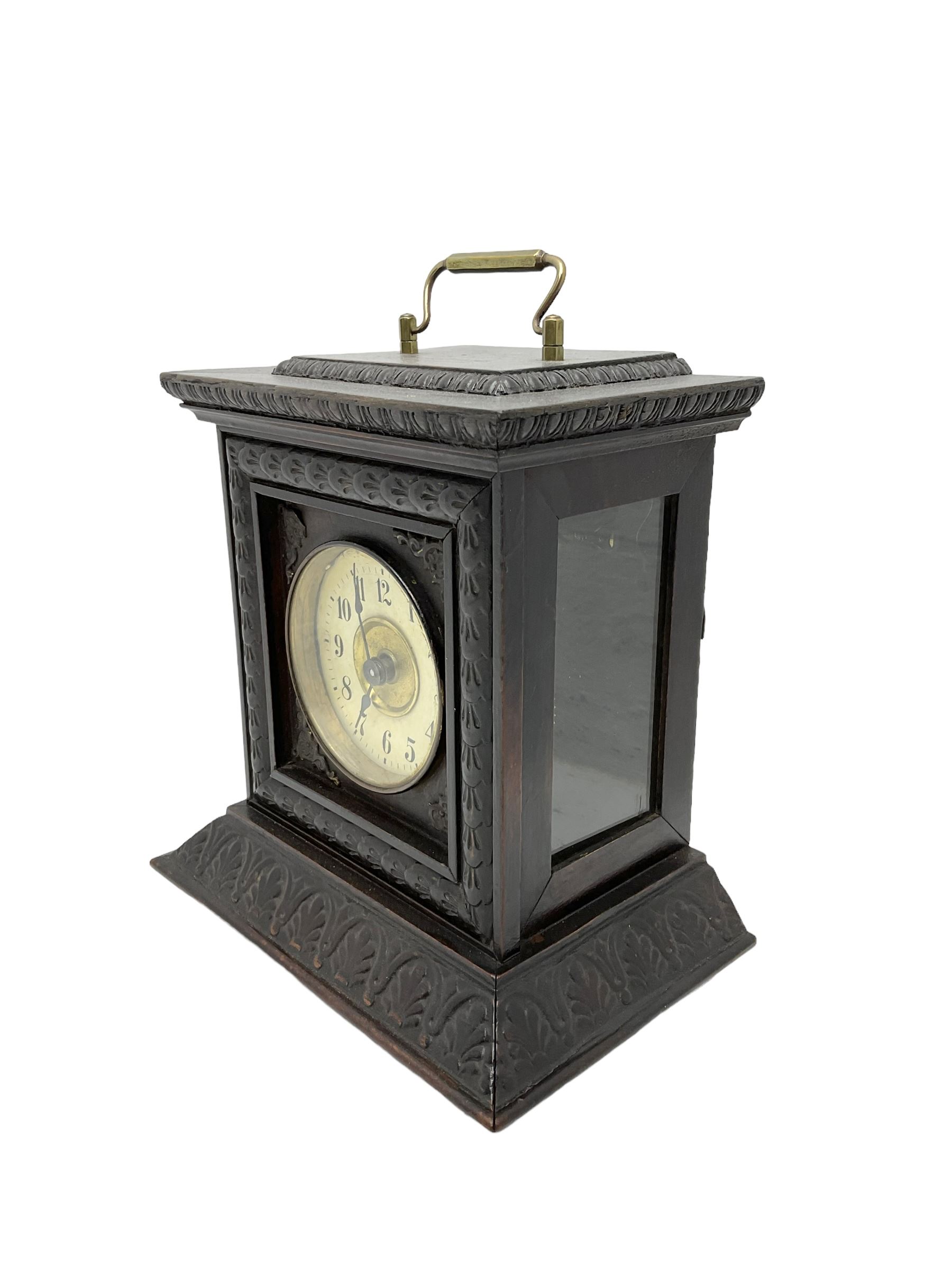 German - late 19th century  Black Forest Junghans alarm clock, profusely carved mouldings with glass side panels and carrying handle, two part dial with a gilt centre, Arabic numerals, minute track and steel spade hands, 30hr  balance wheel movement with alarm sounding on a bell, wound and set from the rear, with Key.