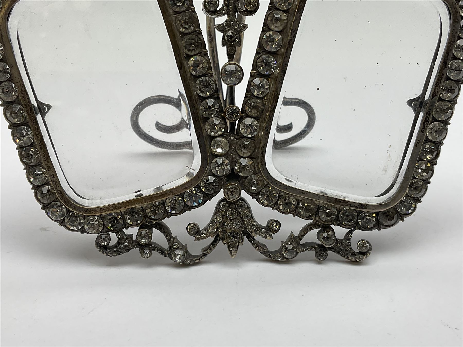 Early 19th century silver plated double photograph frame, each rounded rectangular aperture surrounded by a paste border, with ornate scroll feet and mantling also set with clear paste stones, with easel style support verso, H12cm
