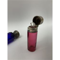 Late Victorian silver mounted ruby glass cylindrical scent bottle, with interior glass stopper, Birmingham 1900, makers mark worn, H8cm, together with a Victorian double ended cut blue glass perfume bottle mounted with white metal screw and flip caps decorated with foliate repousse detailing, H13.5cm