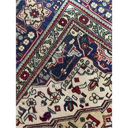 Persian Heriz pale wheat ground rug, indigo pole medallion surrounded by neatly arranged Hac and stylised flower head motifs, indigo main border decorated with alternating palmette motifs, within floral pattern guard stripes 