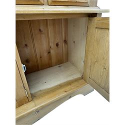 Early 20th century pine kitchen dresser, featuring a hutch with arched top over three open shelves, the base with five drawers over three cupboard doors, turned column supports flanking the doors, scalloped apron base with bracket feet