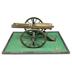 Scratch built brass model of an 1861 Gatling Gun with rotating barrels, hinged cover revealing mechanism, on metal bound wooden spoked wheels and rectangular base L47cm H22cm