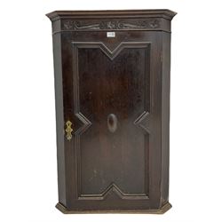 Early 20th century oak corner cupboard, s-scroll carved frieze over single door with geometric mouldings, two interior shelves