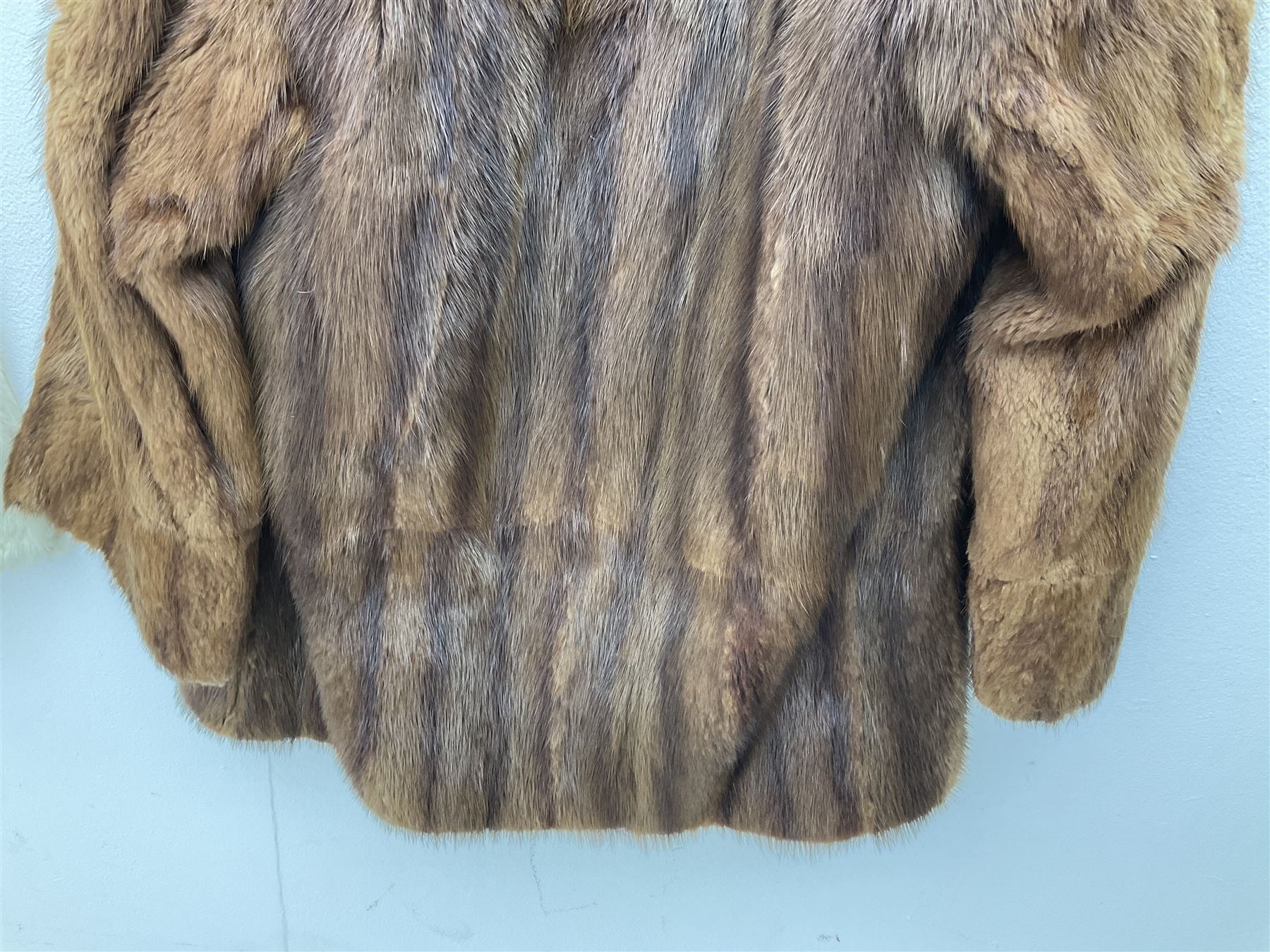 Brown mid length musquash fur coat by National Fur Company together with white rabbit cape