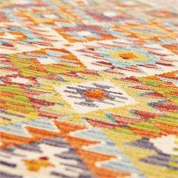 Chobi flatweave kilim runner with a repeating stepped diamond medallion design in live green, rust, teal, purple, and ivory, framed by chevron and geometric borders