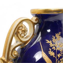 Early 20th century Royal Worcester loving cup, circa 1906, painted with a view of the River Severn and flowers to the reverse, H13cm, Grainger & Co. Worcester twin handled vase, the oval body painted in the Aesthetic style with ferns and grasses in gilt, against a cobalt blue ground, with scrolled handles and quatrefoil foot, H17cm (2)