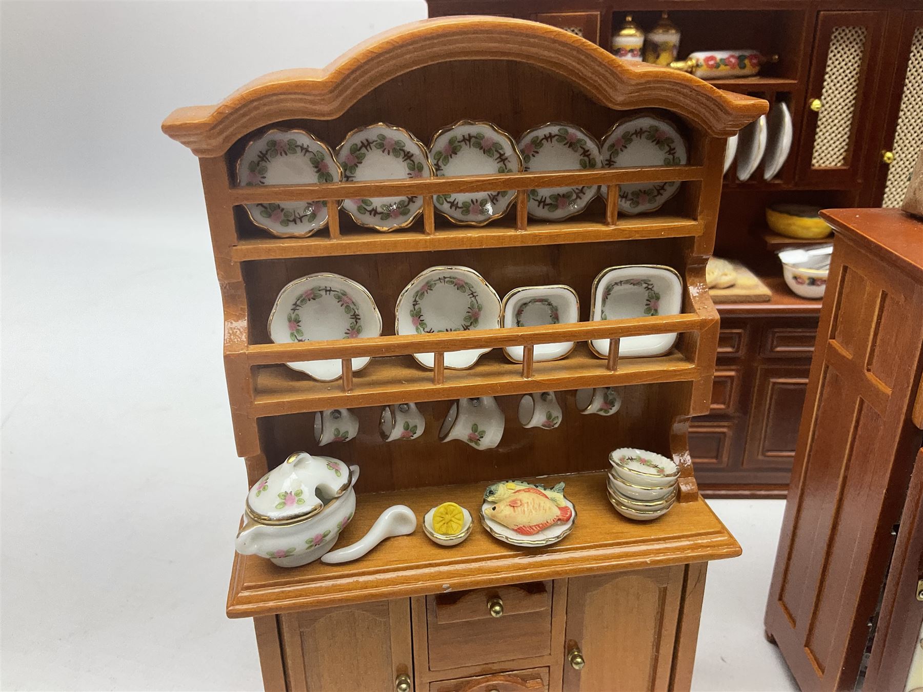 Collection of kitchen and bedroom dolls house furniture, to include two units housing Reutter, Germany ceramic plates, tea wares and accessors comprising one example with a Belfast sink with various pots and pans and jars, the second housing various baking equipment, two dressers, baking table, shelf unit housing various jars of herbs and basket of produce, fridge, and lace and jacquard bedroom suite including bed, pair of bedside tables, dressing table and ottoman