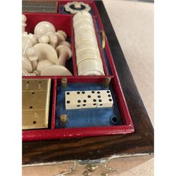 19th century walnut and brass bound games compendium box, painted to enhance the grain, of rectangular form, the hinged opening cover with rounded sides, central brass cartouche with engraved lion crest, and brass riveted straps, opening to reveal a red leather and blue silk lined compartmented interior, with fold-down games board, and lift-out tray containing playing cards, ebony turned dice towers, white and red stained bone draughts, and chess pieces, ivory dice, and ivory and ebony whist markers, and brass bezique board, cribbage board and markers, H15cm W32cm D24cm
This lot has been registered for sale under Section 10 of the APHA Ivory Act