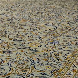 Central Persian Kashan hand-knotted carpet, pale celadon blue ground, decorated with an all-over central floral and foliate design with rosette medallion incorporating scrolling vine work, palmettes, and stylized blossoms  highlighted in tones of indigo, ivory, gold, and powder blue, enclosed by a cream ground border, flanked by multiple guard stripes, with cotton fringe ends 