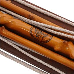 A Woodcock Hill - 20th century travelling coaching whip, the two part yew wood twisted shaft, with leather grip and brass collar and butt cap, with makers mark below the leather handle 'A Woodcock Hill Whip Maker G.I Clothier', together with an additional thong end, mounted upon a wall mounted holder, whip 142cm 
