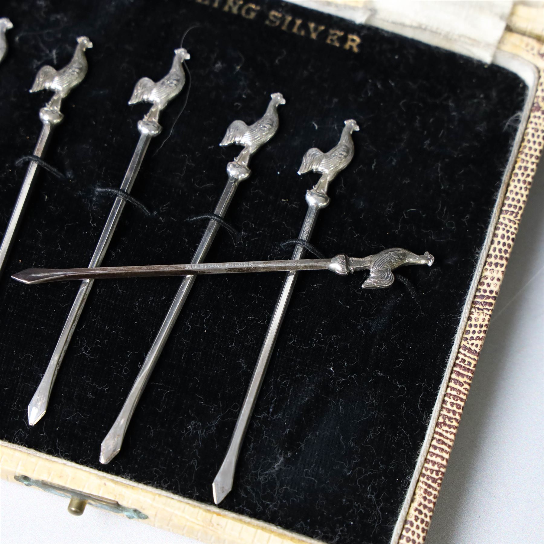 Set of six silver cocktail sticks, each with cockerel finials, stamped Sterling Silver, in fitted case