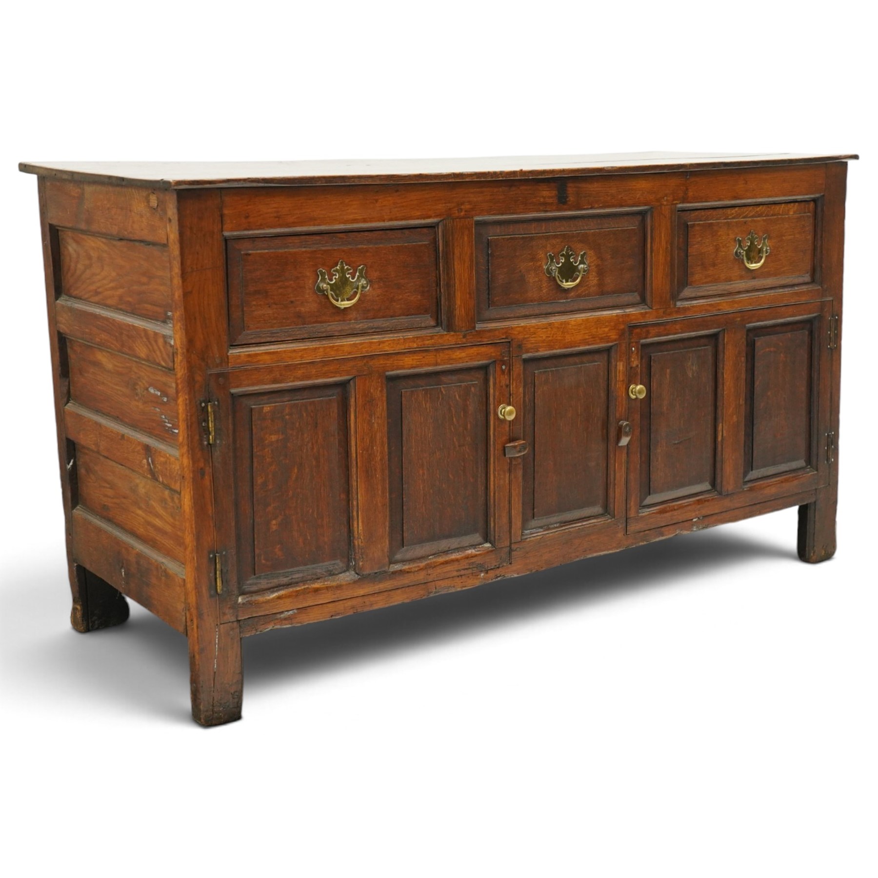 18th century oak dresser base, rectangular top over three drawers, fitted with twin panelled hutch-cupboard doors flanking central fielded panel, raised on stile supports