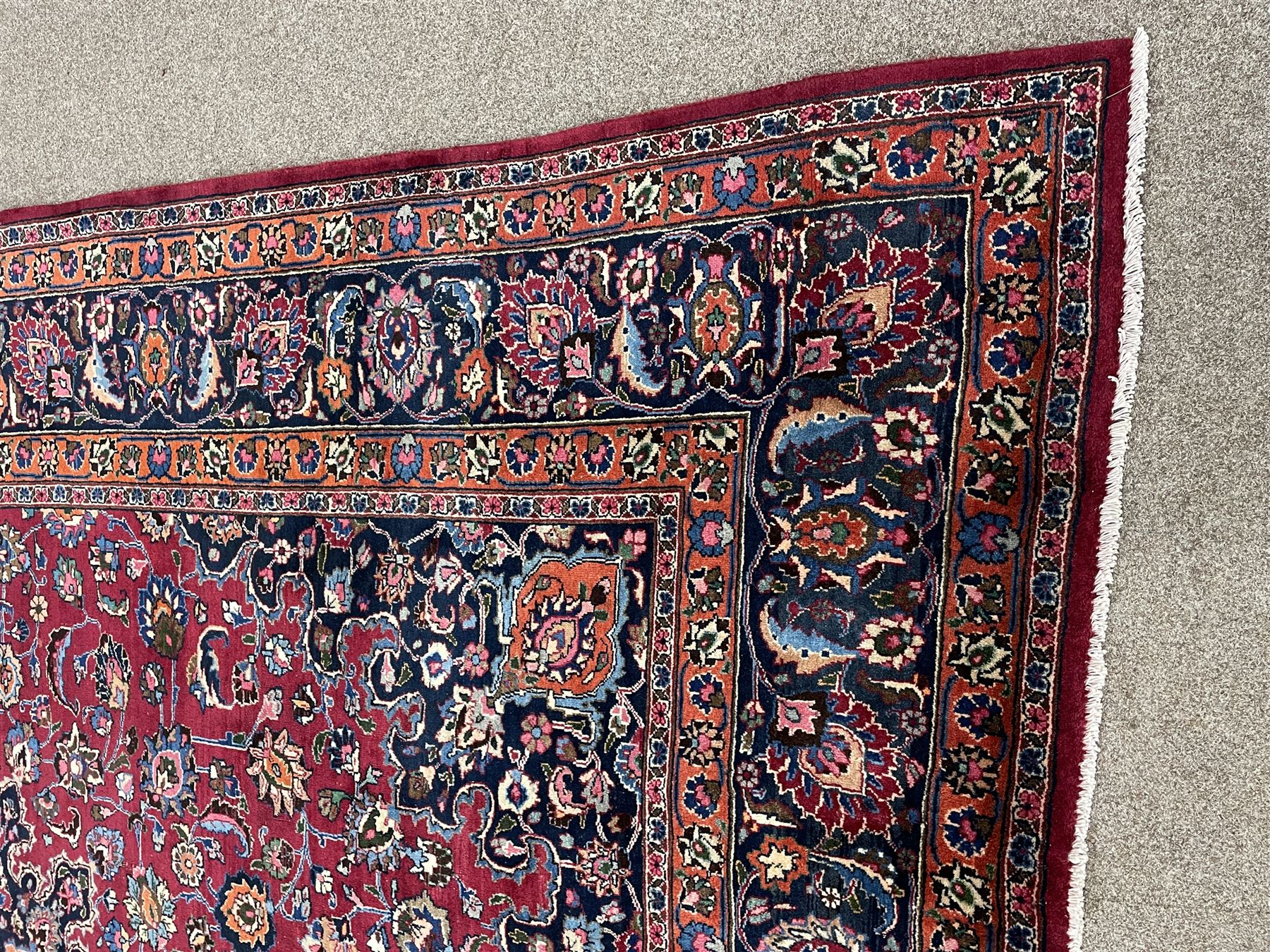 Persian Meshed carpet, plum ground and decorated with stylised flower heads and interlacing foliate, large central stylised medallion with orange detail, the orange mirrored in the five band border decorated with scrolling floral design, signature panel to end 
