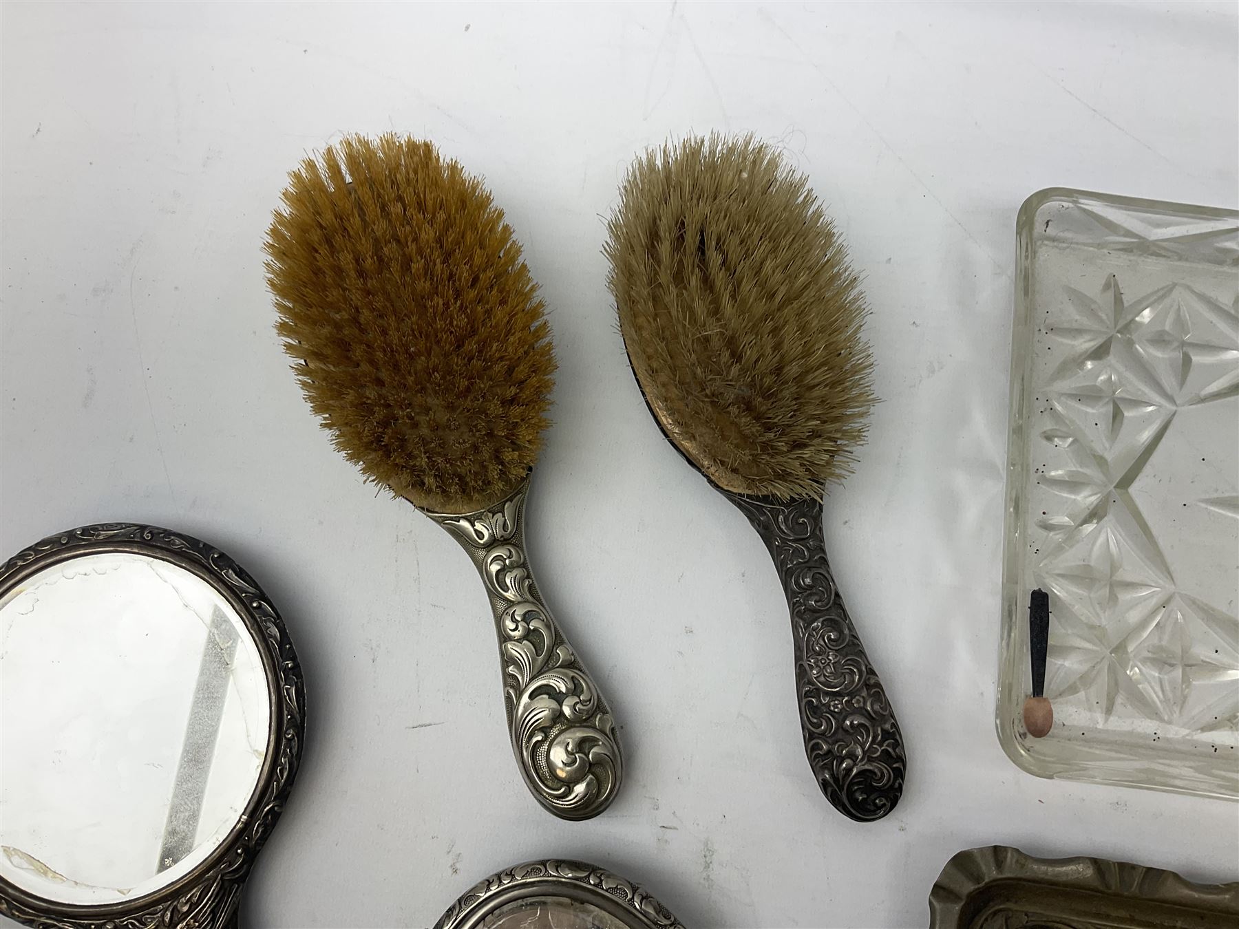 Glass dressing table tray, scent bottles and lidded bowl, metal mounted foliate design hair brushes and handheld mirrors etc