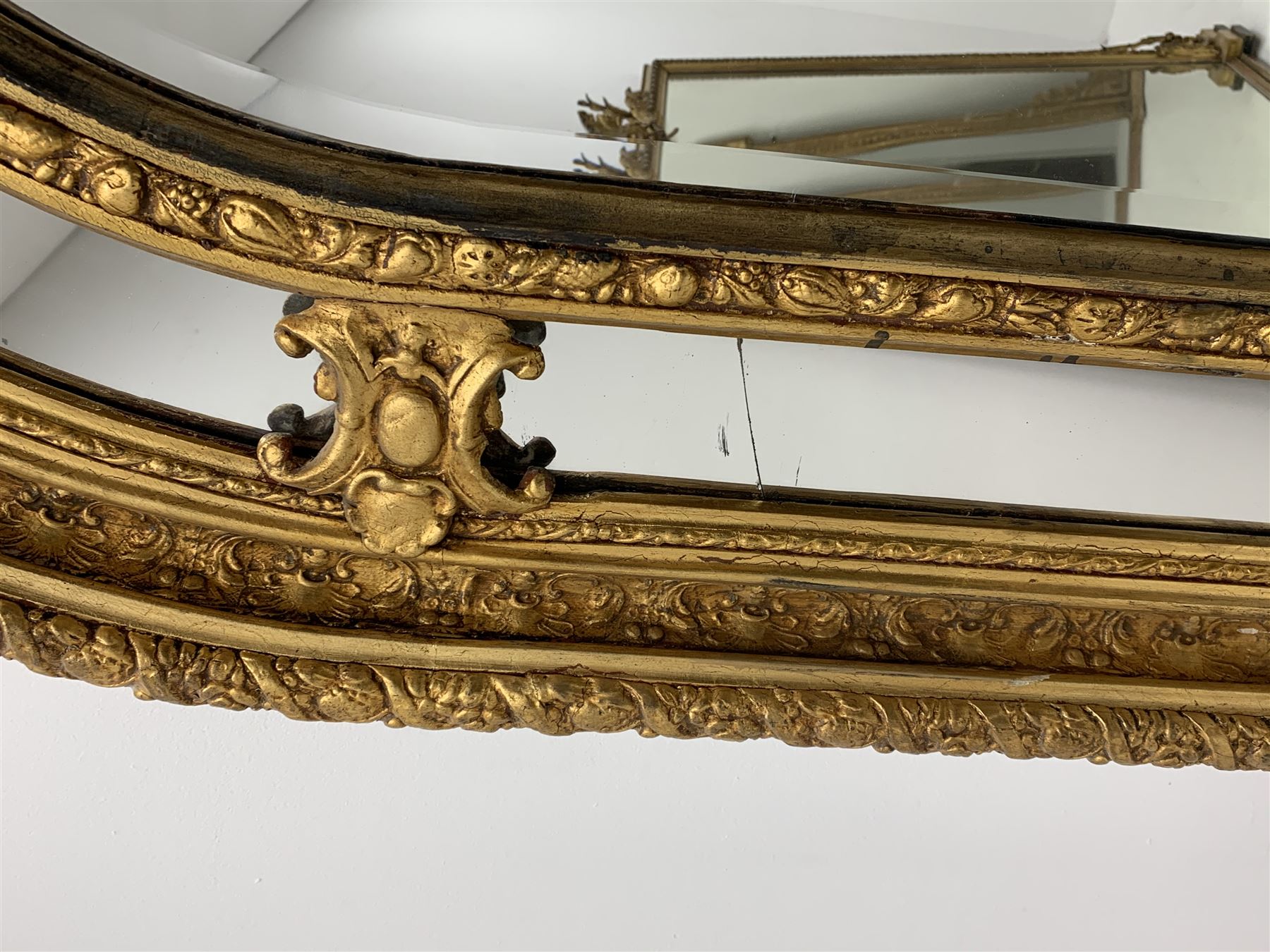 Gilt Rococo style mirror, arched top with central cartouche and oak leaf moulded pediment, floral and fruit moulded surround with segmented glass panels, bevelled central pane, c-scroll shell and acanthus leaf brackets