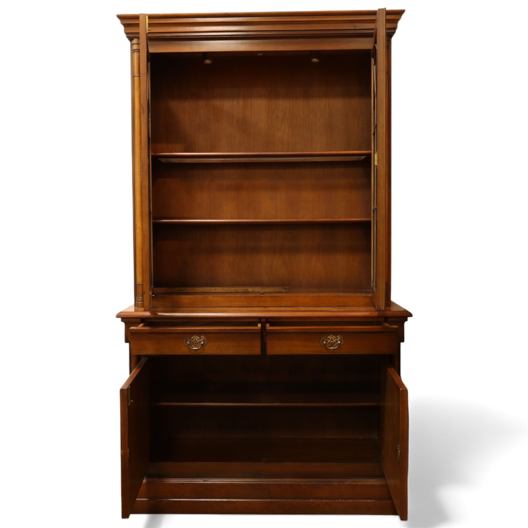 Edwardian mahogany bookcase cabinet, the moulded cornice above a pair of astragal glazed doors with gothic arched tracery, enclosing adjustable shelving, the projecting mid section fitted with two short drawers, over a pair of panelled cupboard doors with arched detailing, flanked by turned and pilasters, raised on a moulded plinth base