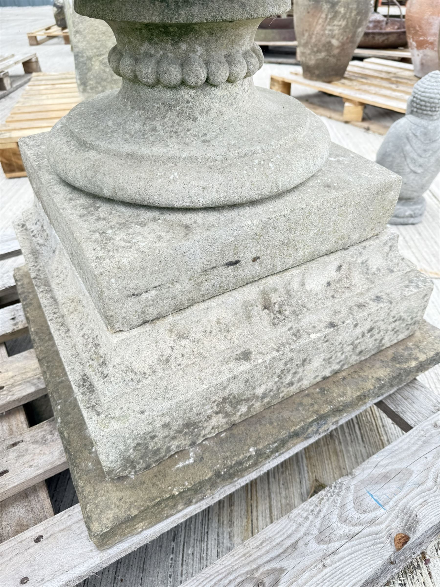 Pair of large weathered Country House Haddonstone garden urns, acanthus carved rim above gadrooned bowl, beaded detailing to the neck, raised on stepped double plinth base
