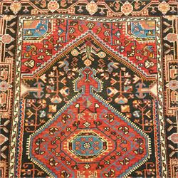 North West Persian Heriz hand-knotted rug, indigo and madder red field with a central angular medallion with stylized floral and geometric motifs within multiple patterned borders with fringe ends 