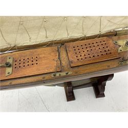 Early 20th century large pond yacht with mahogany hull, stained pine keel with brass rudder, simulated deck hatches and brass fittings, rigged as a staysail schooner (?) with four sails L117cm H148cm; loose mounted on stained pine stand