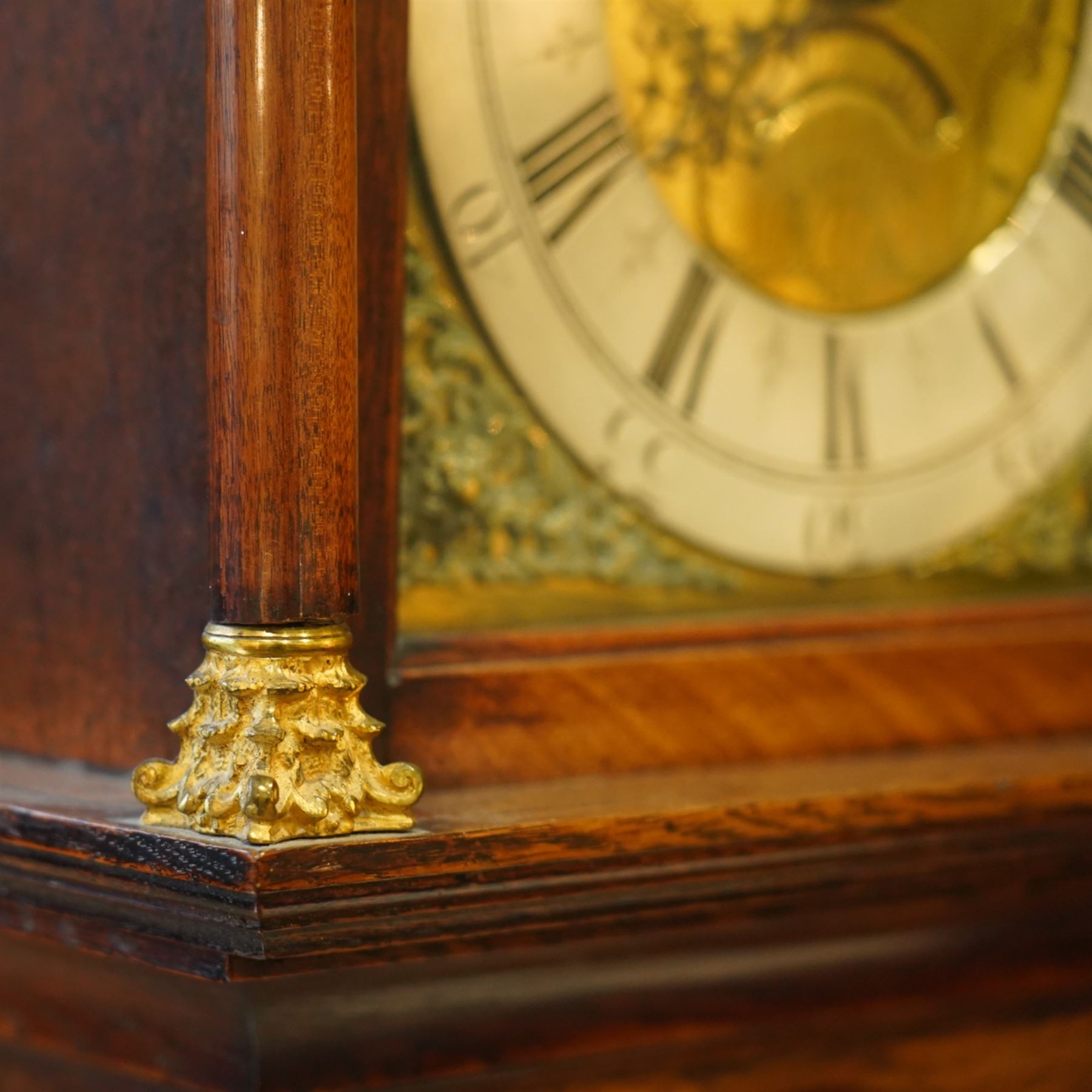 Gilbert Kidd of Malton-oak cased mid-18th century 30hr longcase clock, with a caddy top and three gesso finials, square hood door flanked by turned pilasters with Corinthian capitals, trunk with a long wavy topped door on a square plinth with an shaped skirt, brass dial with an engraved dial centre, date aperture and steal hands, silvered chapter ring with Roman numerals and five minute Arabic's, dial pinned to a chain driven countwheel striking movement. With a brass cased weight and pendulum. 