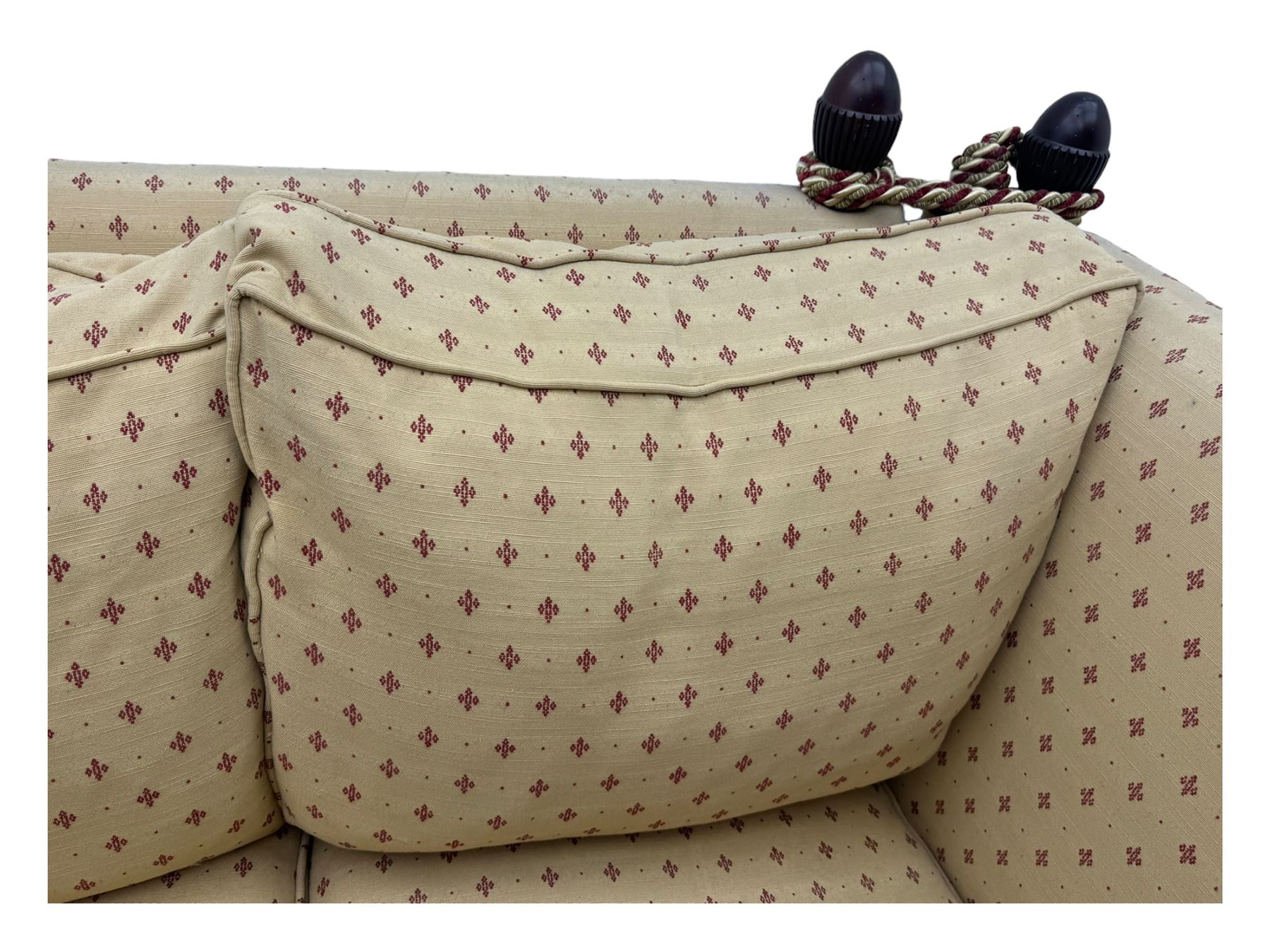 20th century Knole design two seat sofa, high back and double drop-arm joined by mahogany finials and ties, upholstered in camel ground fabric with red lozenge design, on turned supports with brass castors