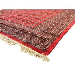 Persian Bokhara crimson ground carpet, the field decorated with repeating Gul motifs and lozenges, the multi-band geometric border with stylised plant motifs, two additional bands at the ends with geometric lozenges