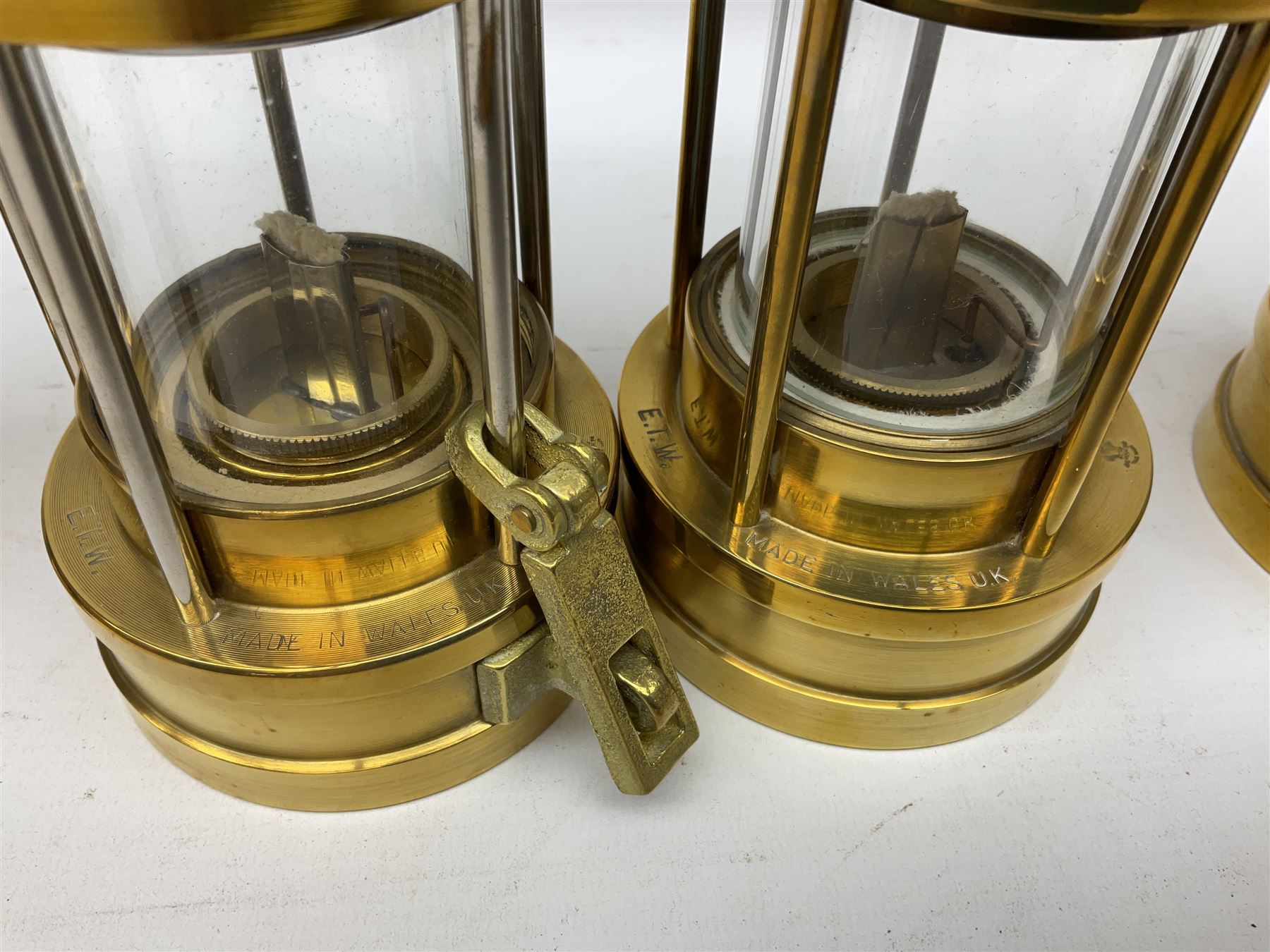 Four miners lamps, comprising Clanny miners lamp, with flip top and gauze protected by three rods, stamped E.T.W E-3, lamp with a gauze chamber protected by three rods, and two E. Thomas & Williams Ltd lamps, tallest example H26cm
