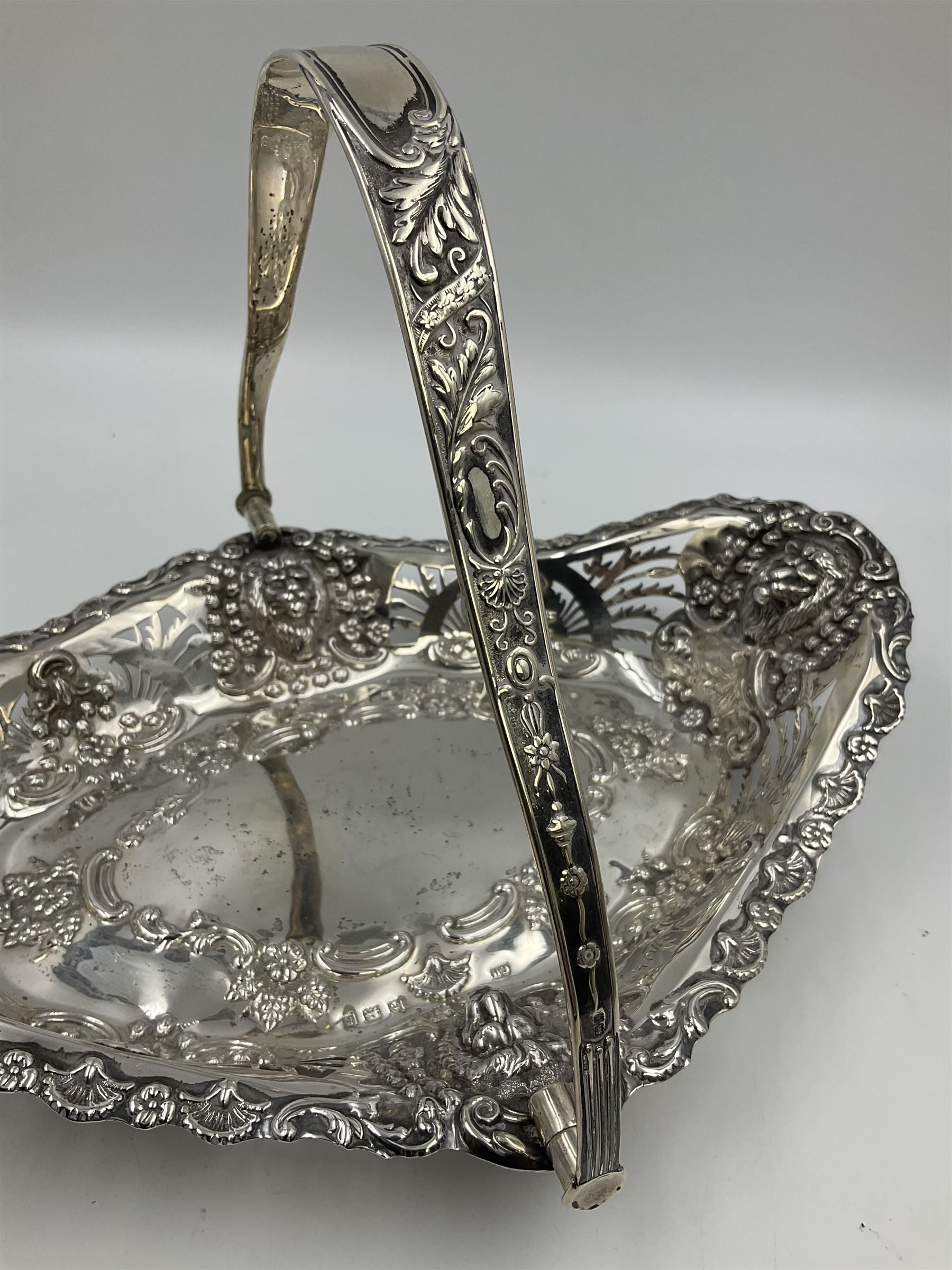 Edwardian silver swing handled basket, of navette form, with four repousse lion masks to each corner and with pierced and embossed floral, scroll and shell decoration to sides, base and handle, hallmarked Charles Horner, Birmingham 1906, height including handle H20cm