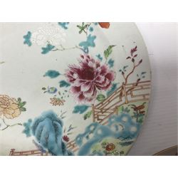 Three 18th century Chinese Famille Rose plates, the first example enamelled with blossoming peonies, rockwork and fence, the other two examples of similar design, decorated with blossoming peonies and sprigs within shaped inner borders, each approximately D23cm