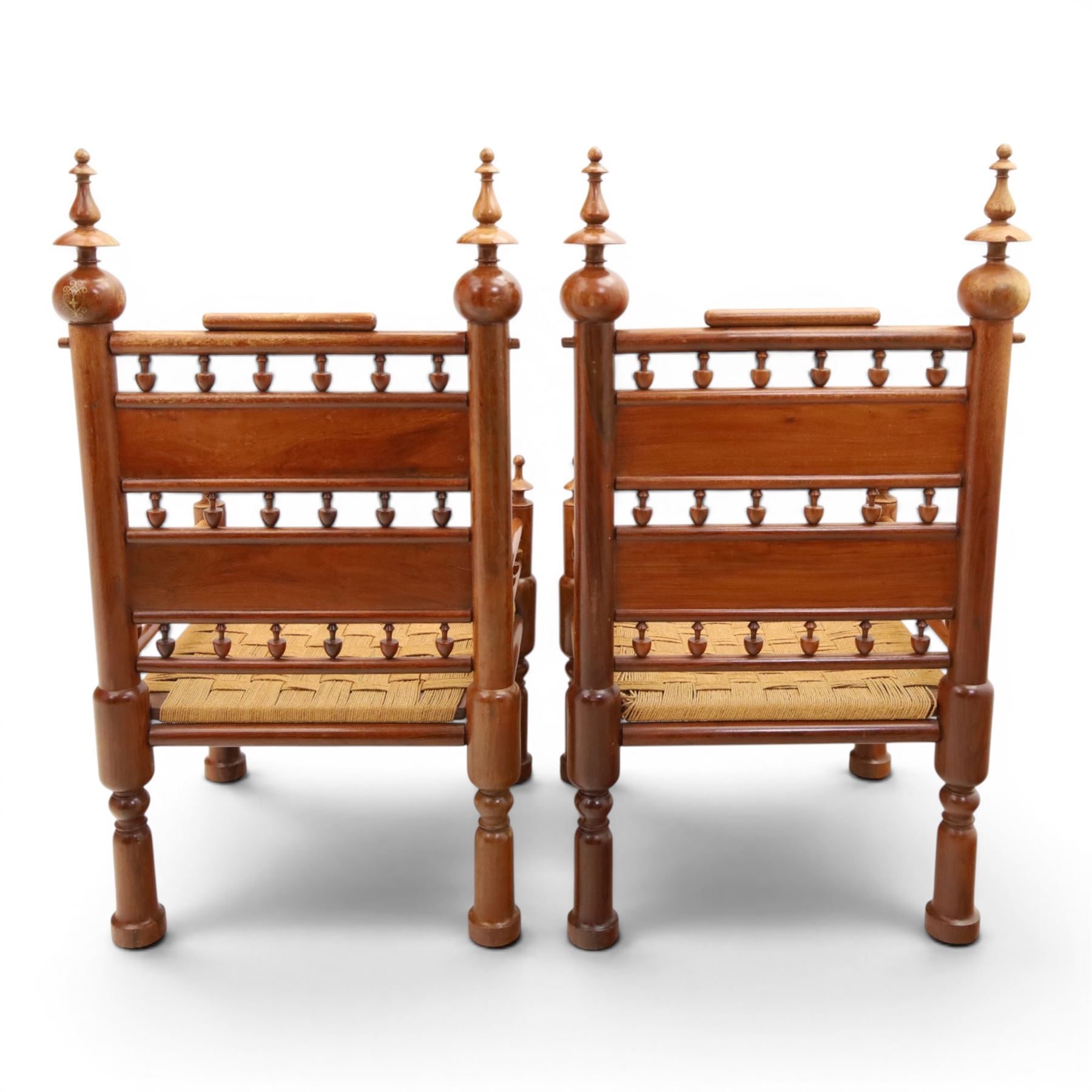 Pair of Anglo-Indian brass inlaid hardwood low chairs, the backs with turned spindle rails and rectangular panels inlaid with scrolling foliate decoration, woven rush seats within moulded frames, raised on turned supports with ring turned feet