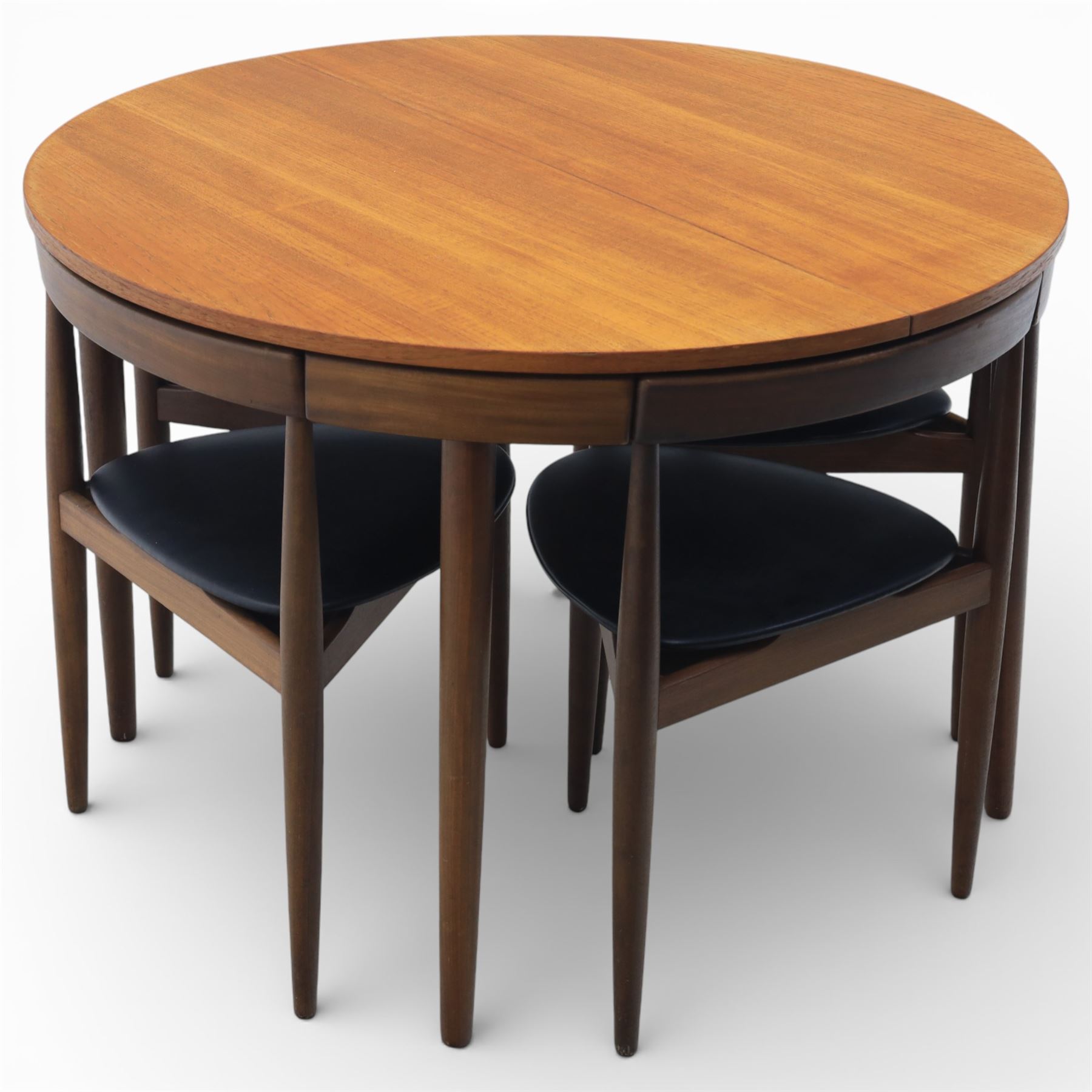 Frem Røjle - Danish teak 'Roundette' extendable dining table, circular top with softly chamfered edge and internal stowable leaf extends to 156cm, raised on four tapered cylindrical legs, accompanied by four matching dining chairs with shaped teak frames and black vinyl upholstered seats, the chairs designed to nest beneath the table when not in use