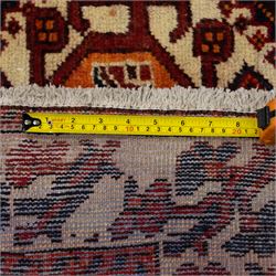 South West Persian Cori hand-knotted rug, red field with three central stepped lozenge medallions enclosing stylized geometric motifs surrounded by scattered rosette devices and angular ornaments within multiple geometric borders, with fringe ends  