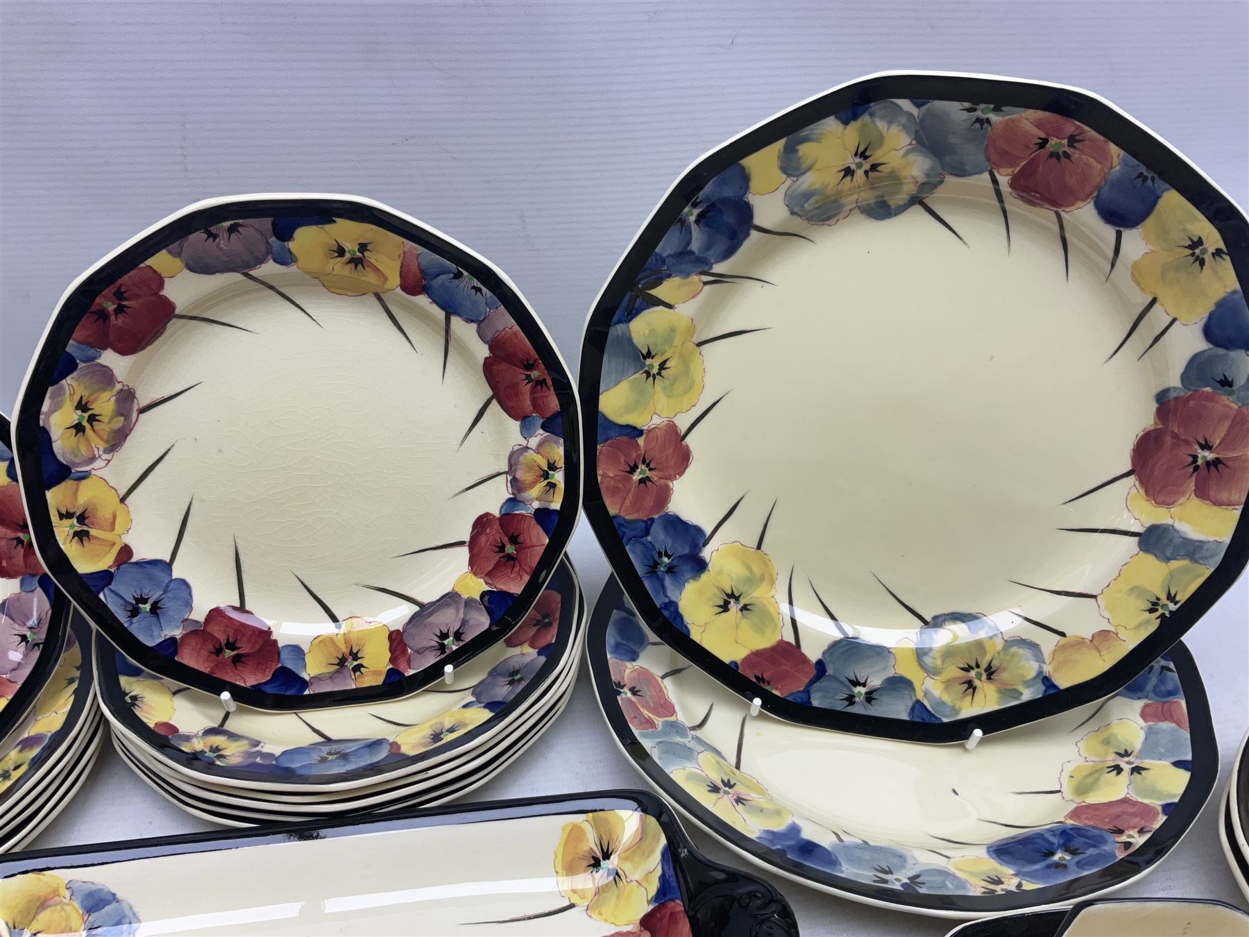 Early 20th century Art Deco Royal Doulton Pansies pattern octagonal teawares, comprising three larger teacups and saucers, three smaller teacups and saucers, open sucrier, two jugs, slop bowl, six side plates, two larger plates, two small circular dishes and one long twin handled rectangular dish, all with printed marks beneath, Rd No 597783, pattern no D4049