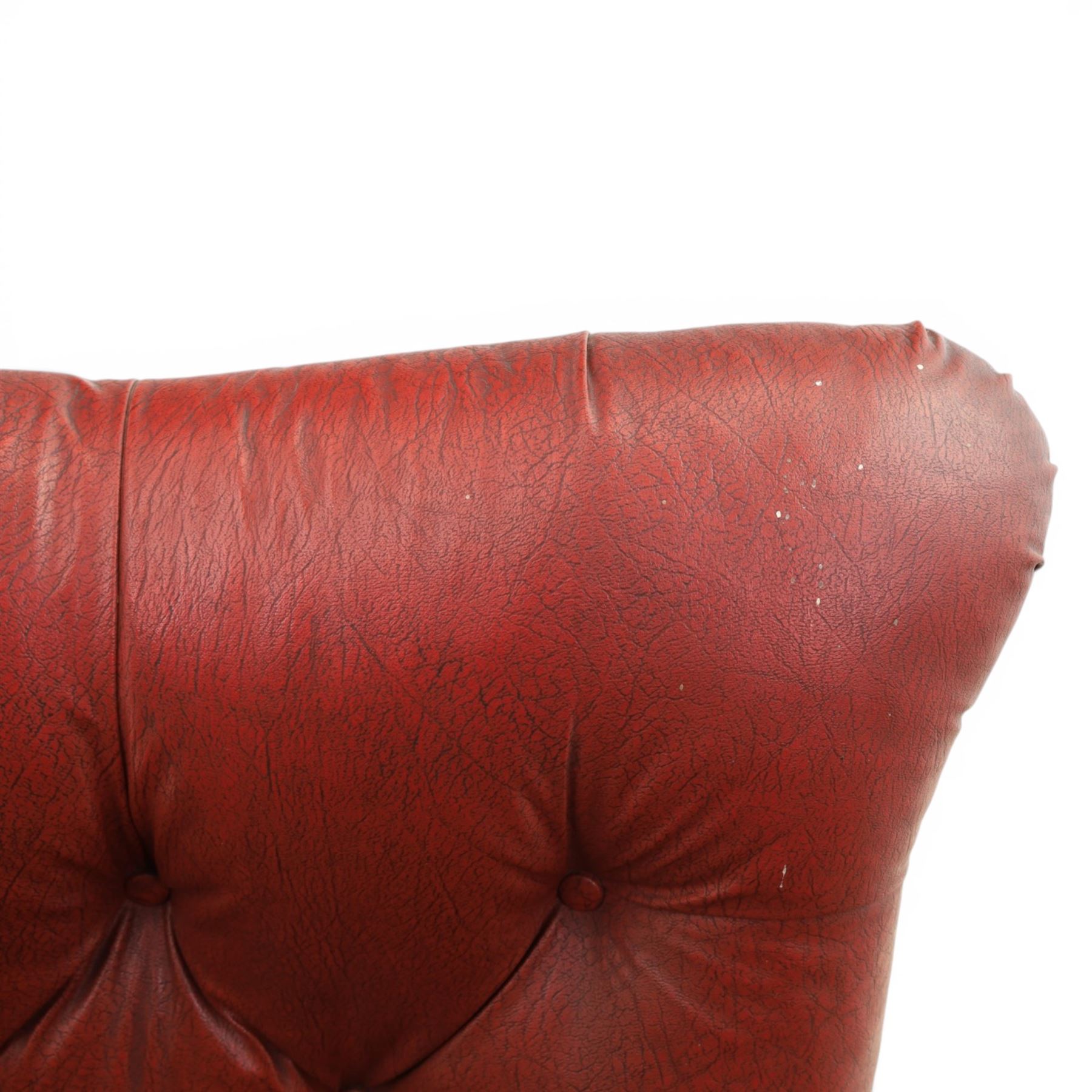 Early 20th century style oxblood red leather Chesterfield armchair, deep buttoned shaped back over padded scroll arms and loose seat cushion, raised on turned mahogany front supports with brass caps and castors