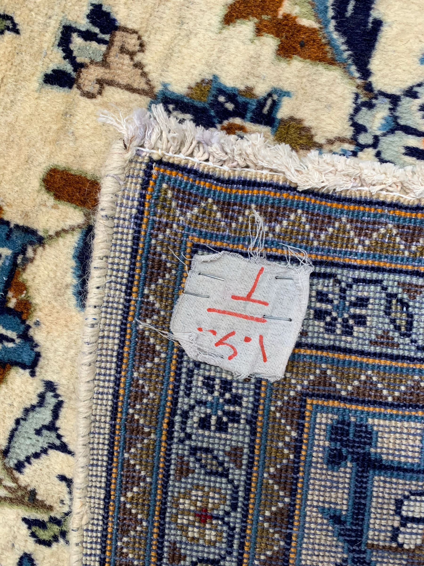 Persian Kashan ivory ground rug, the field decorated with stylised plant motifs and interlacing leafy branches, scrolling border decorated with further plant motifs, floral design guard bands  