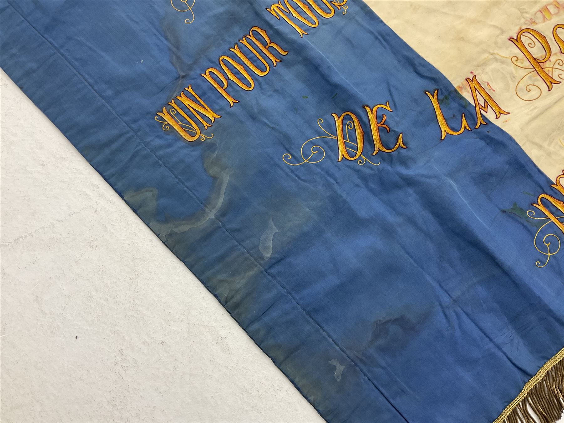 French State Police banner as the tricolor flag embroidered with coloured and metallic thread 'Societe De Secours Mutuels Un Pour Tous Tous Pour Un De La Police D'Eteat De Marseille' to one side; plain flag verso; tassels to three sides 100 x 113cm