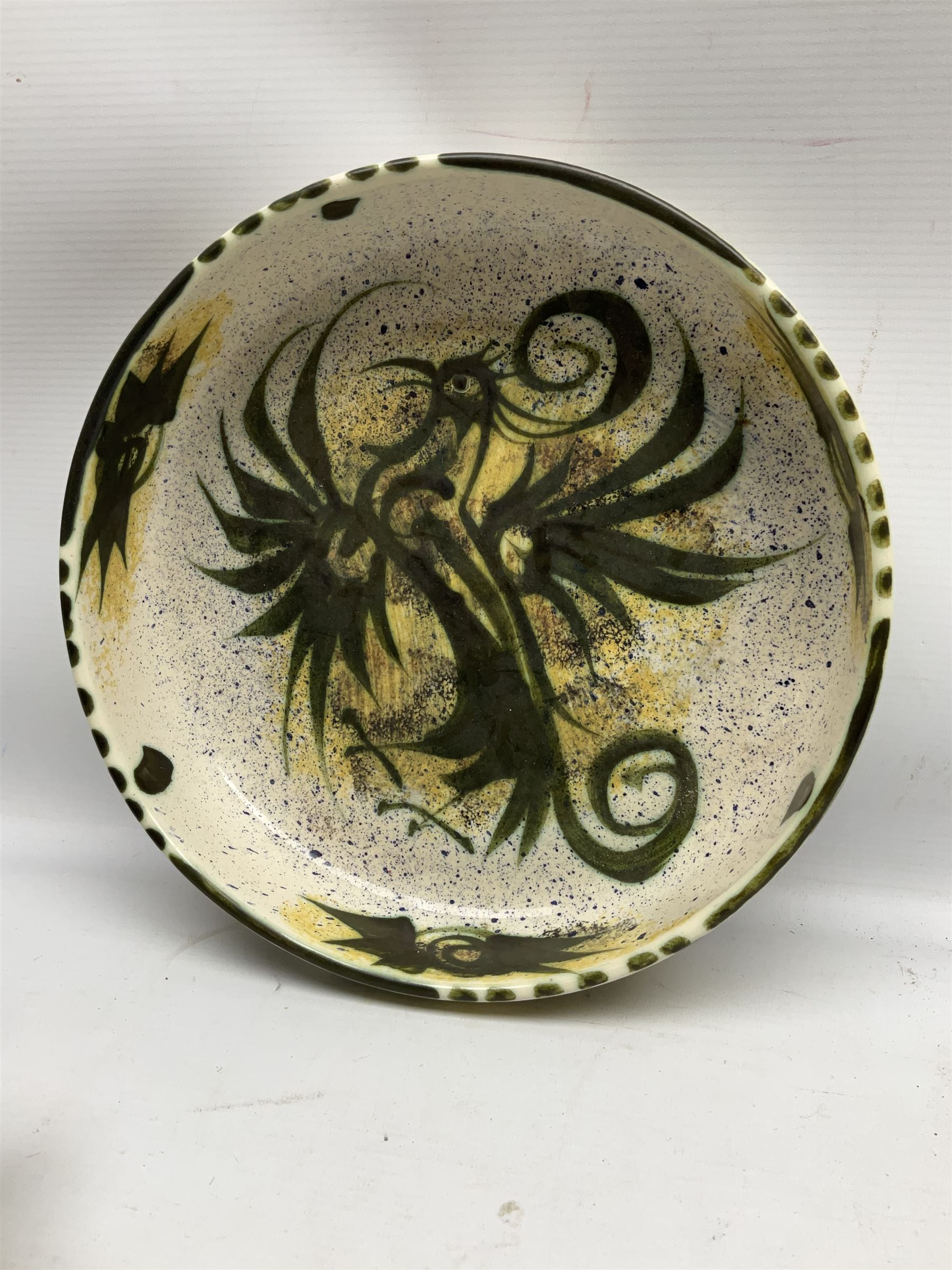 20th century Celtic Pottery, Newlyn, table lamp of tapering form, cylindrical vase and shallow bowl, all decorated with a dark stylised phoenix, modelled with wings outstretched upon sponged ochre, blue and cream ground, bowl D26cm