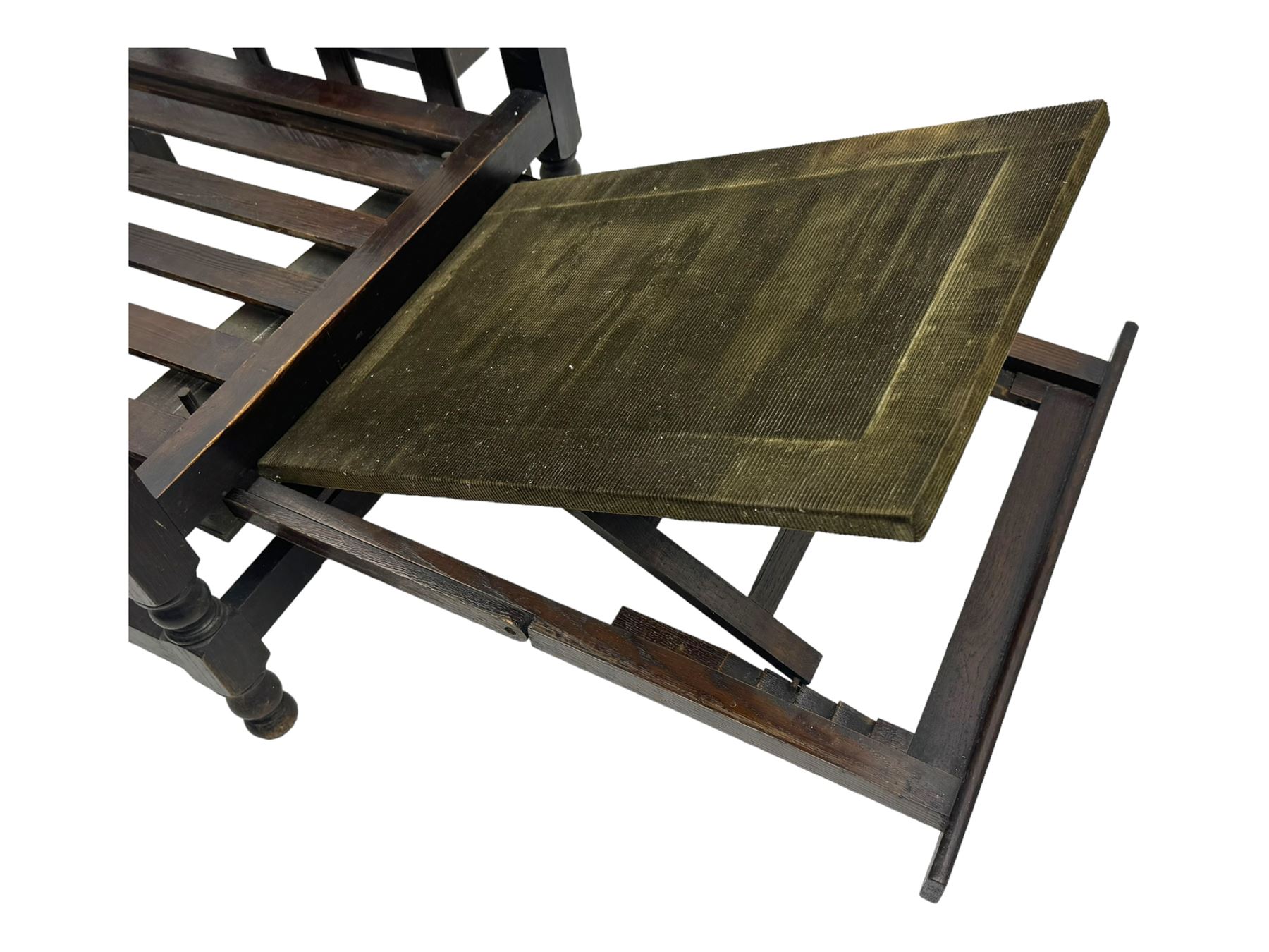 Late Victorian oak steamer chair, adjustable slatted backrest with grooved crest rail, wide armrests extending to a sliding adjustable footrest, open frame sides with vertical slats, side magazine rack and collapsible table, raised on turned front supports