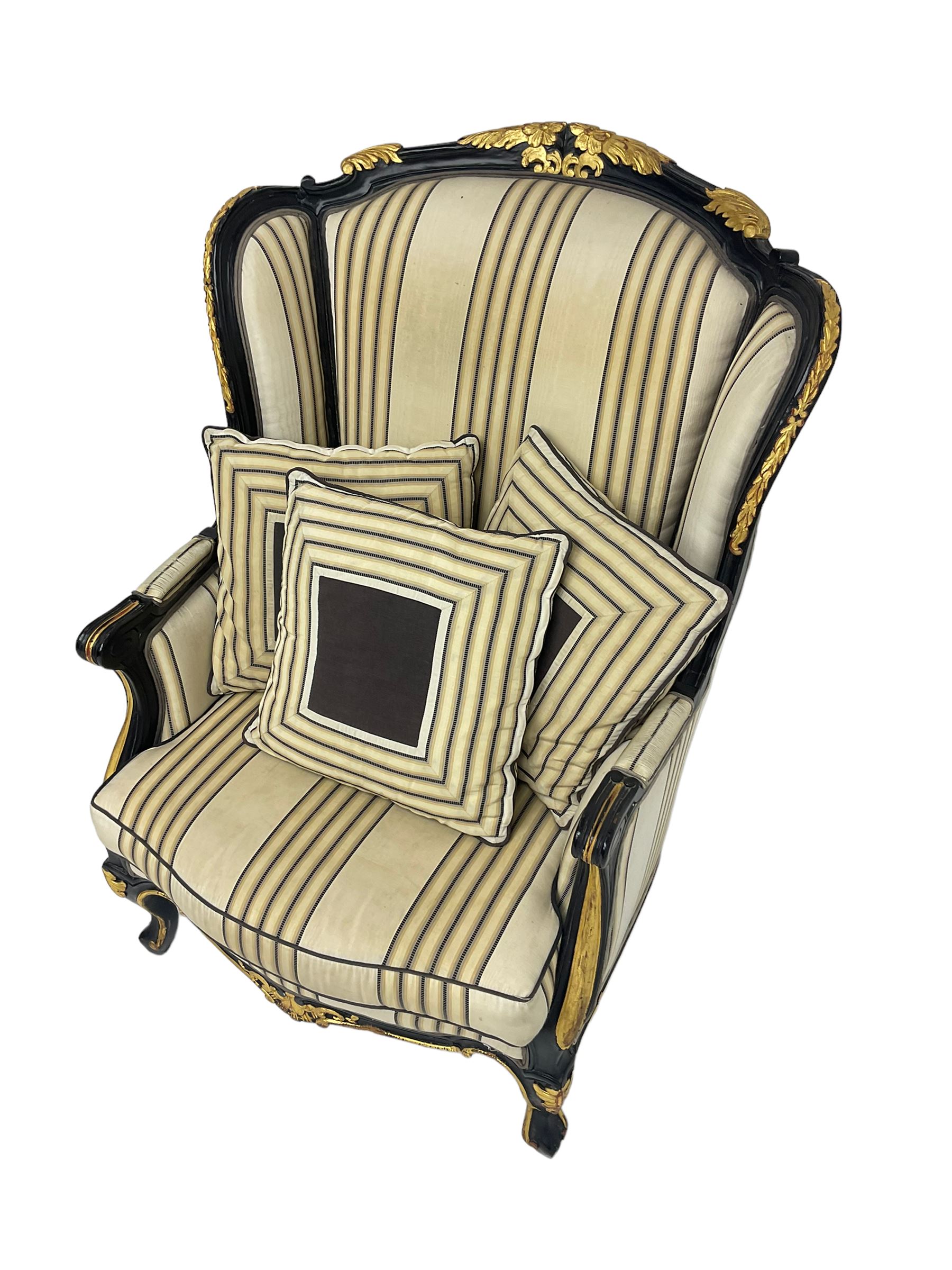 Thomas Messel - Georgian style ebonised and gilt wingback armchair, upholstered in striped fabric, on cabriole front feet