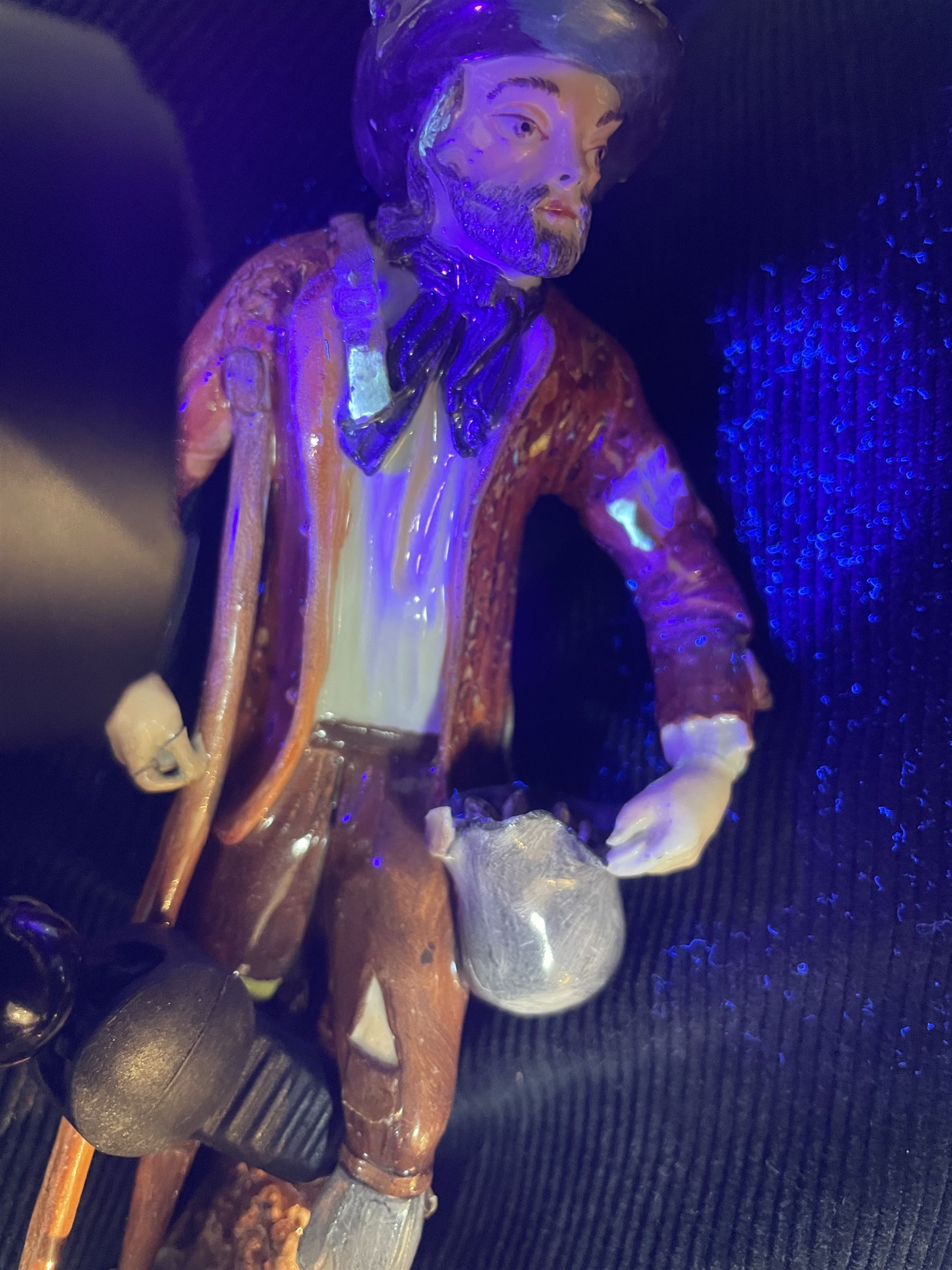 Mid 18th century Furstenberg figure, modelled as a beggar or mendicant with peg leg and bare foot, circa 1755, modelled by Simon Feilner, wearing tattered clothes, one arm supporting an alms pouch, the other holding a crutch, upon a part scrolled base, bearing paper labels beneath including one inscribed 'Sammlung Wilhelm Gumprecht 322', H15cm