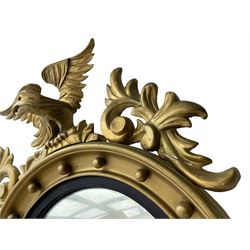 Pair of Regency period giltwood convex wall mirrors, moulded circular frame decorated with spherical mounts surmounted by a carved eagle with spread wings, foliage scroll carved upper and lower brackets, reed moulded and ebonised slip enclosed convex mirror plate 