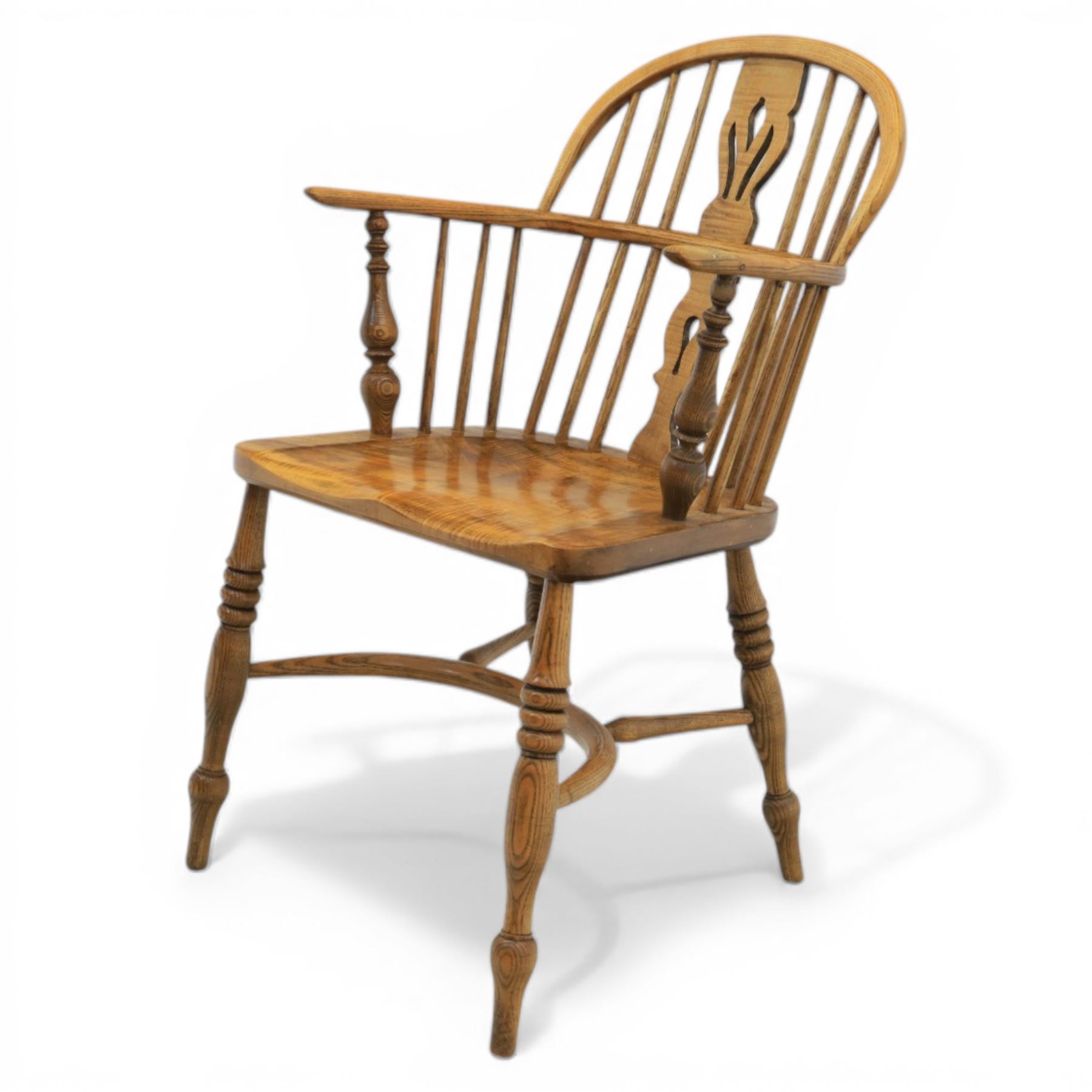 Late 20th century elm and beech low back country Windsor armchair, the arched hoop back with central pierced splat and turned spindles, shaped arm rail on turned supports, saddle seat, raised on turned legs united by a crinoline stretcher