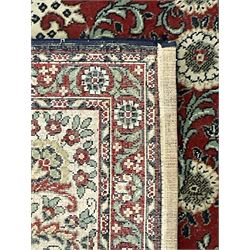 Persian design crimson ground carpet, the central rosette medallion surrounded by scrolling leaves and flower heads, the spandrels decorated with floral design and scrolling foliage, repeating border within guard stripes