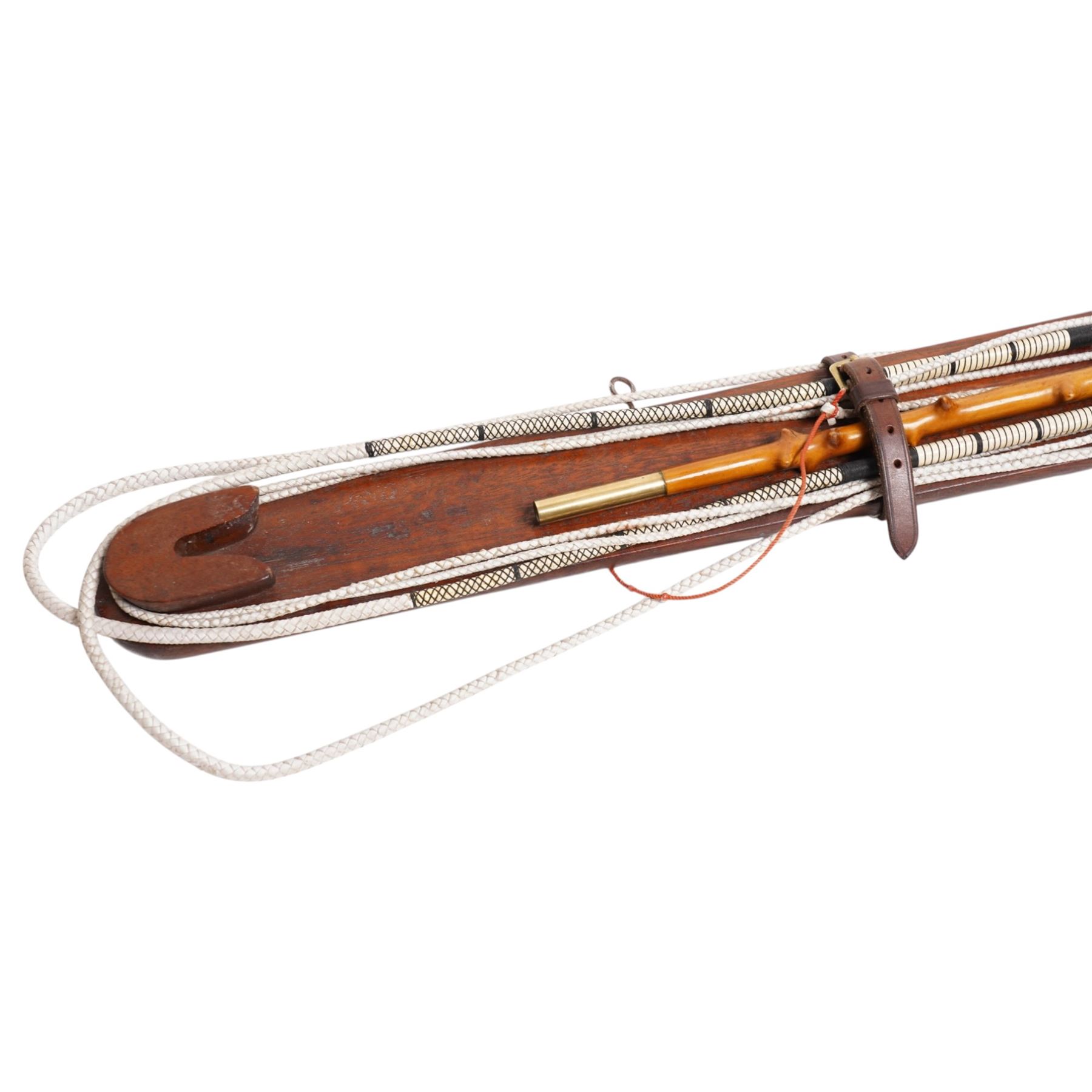 A Woodcock Hill - 20th century travelling coaching whip, the two part yew wood twisted shaft, with leather grip and brass collar and butt cap, with makers mark below the leather handle 'A Woodcock Hill Whip Maker G.I Clothier', together with an additional thong end, mounted upon a wall mounted holder, whip 142cm 