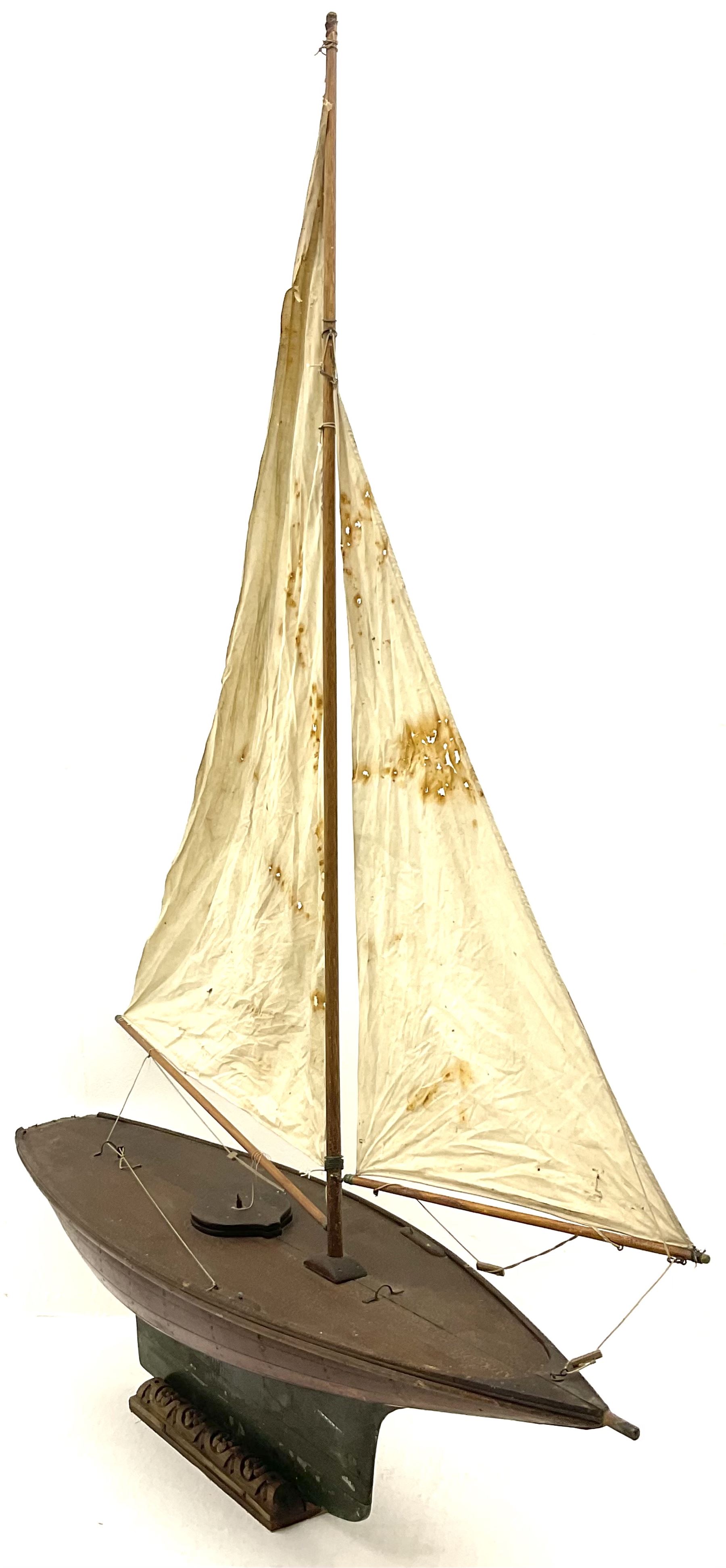 Large Victorian pond yacht, the planked hardwood hull with large lead weighted keel and working rudder, simulated planked deck and single mast with original sails; on later scratch-built wooden stand L117cm H151cm